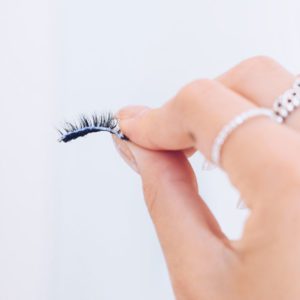 Woman's hand holding a fake eyelash.