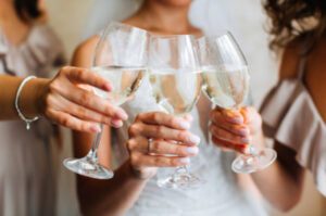 Women only showing their hand with wine glasses cheering.